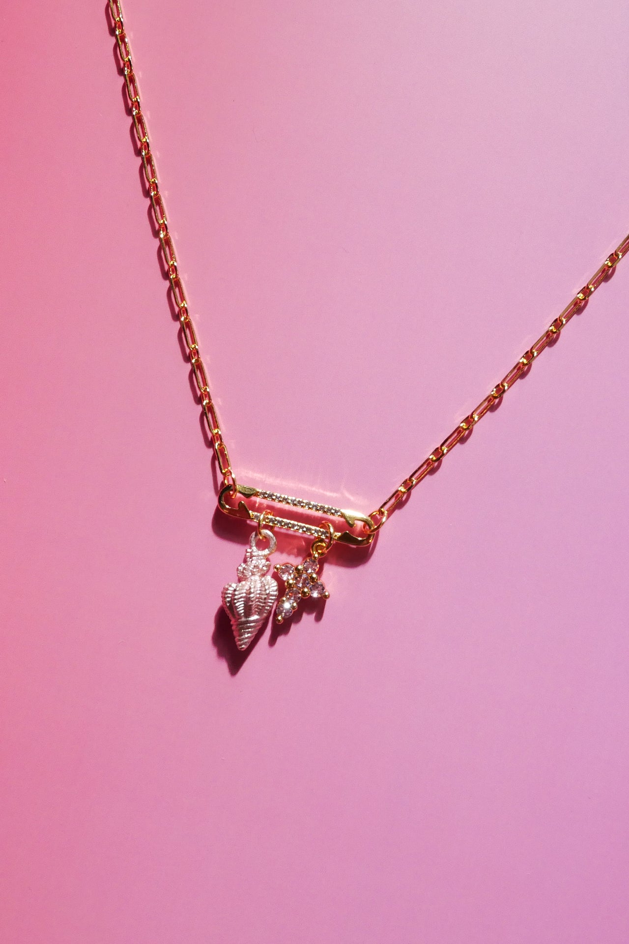 Pink CZ cross and pink seashell charm necklace on an 18k gold-plated paperclip chain with pavé safety pin link
